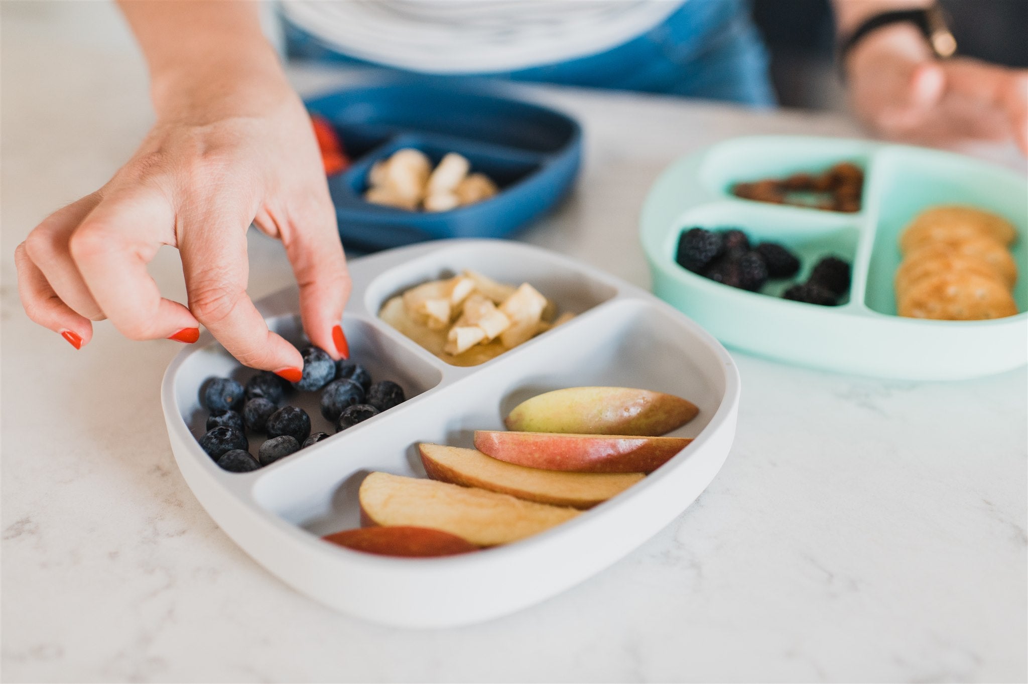 blueberries, bananas, and apple slices on grey divided suction plate