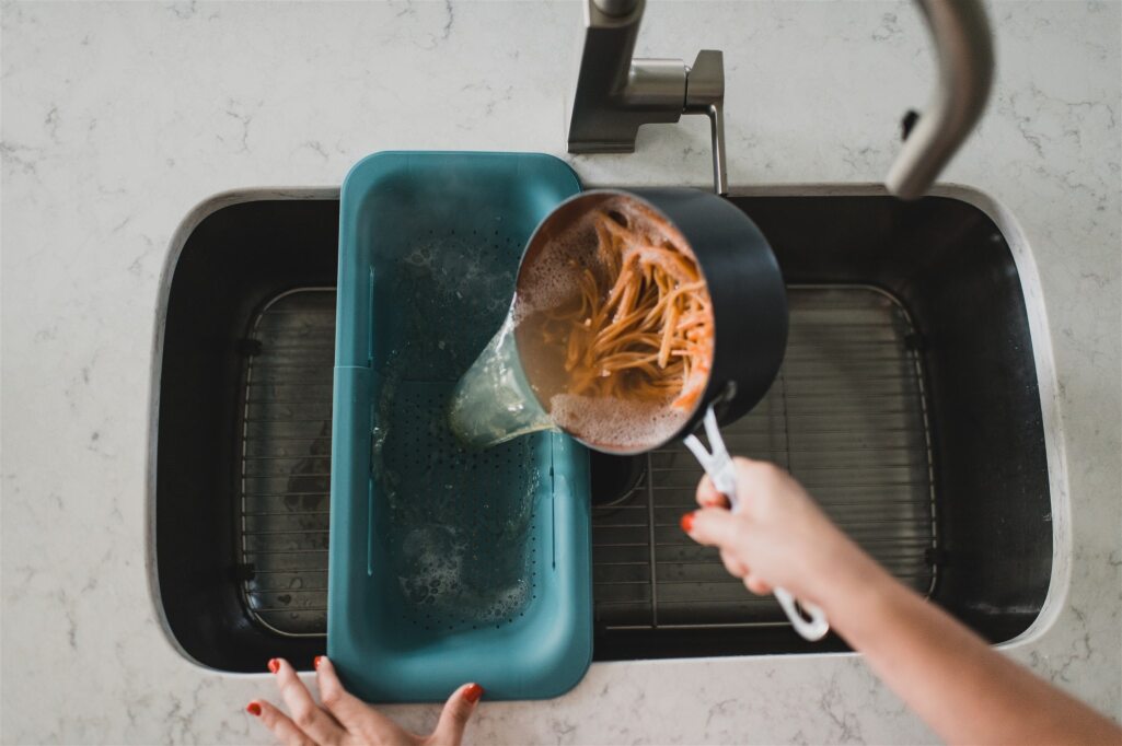 Blue over the sink colander being used to drain pasta. 